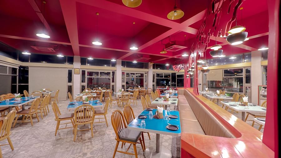An image of a restaurant in Pride Resort Ambaji featuring tables and chairs at each corners of the room